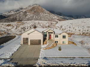 View of front of house with board and batten siding, a garage, concrete driveway, and a mountain view