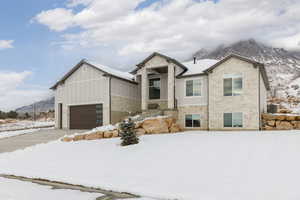 View of front of house with stone siding, a mountain view, board and batten siding, and a garage