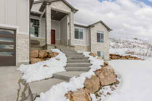 View of front of home with stone siding, board and batten siding, a porch, and a garage