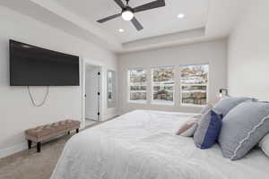 Bedroom with a tray ceiling, ceiling fan, light carpet, and recessed lighting