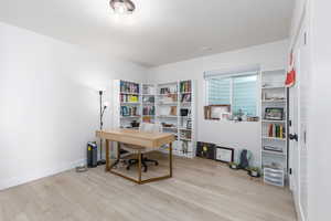 Home office featuring light wood-type flooring and baseboards
