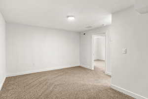 Empty room with light carpet and a textured ceiling
