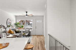Living room featuring light wood finished floors, ceiling fan, and a textured ceiling