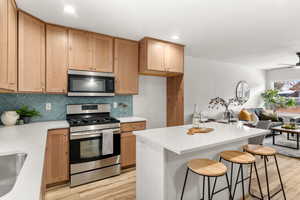 Kitchen featuring stainless steel appliances, a breakfast bar area, light stone countertops, open floor plan, and a center island