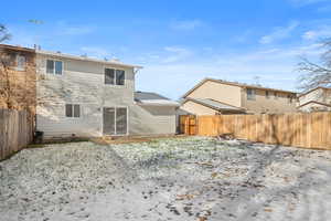 Snow covered property featuring a fenced backyard and a chimney