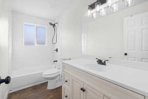 Bathroom with dark wood-style floors, vanity, and shower / bath combination