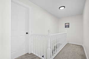Hallway featuring an upstairs landing and carpet