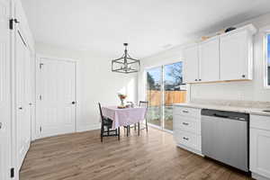 Kitchen featuring pendant lighting, dishwasher and white cabinetry