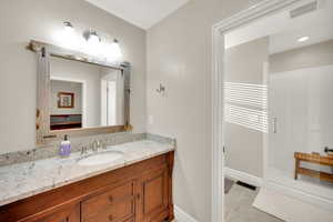 Full bath with light tile patterned flooring, vanity, and a stall shower