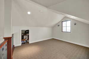 Bonus room loft with light colored carpet and lofted ceiling