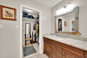 Bathroom featuring a spacious closet, vanity, and light tile patterned floors