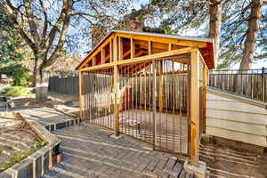 Wooden deck featuring a dog run, a patio area, a fenced backyard, and an outdoor structure