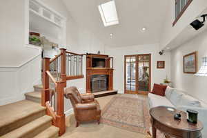 Family Room with a skylight, a glass covered fireplace, a decorative wall, a wainscoted wall, and stairway