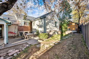 Rear view of house featuring a storage shed, brick siding, and outdoor dining area