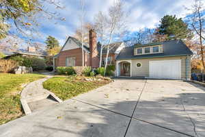 View of front of property featuring concrete driveway, a garage, a front lawn, and a shingled roof