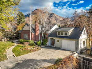 View of front of home with driveway, roof with shingles, a mountain view, and a chimney