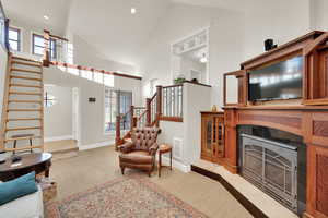 Family room with stairs, high vaulted ceiling, light colored carpet, a fireplace with flush hearth, and recessed lighting