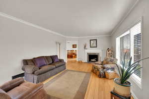Living area with wood finished floors, crown molding, and a tile fireplace