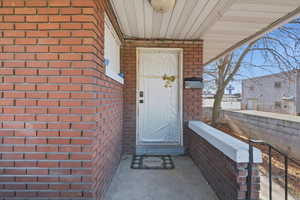 Property entrance featuring brick siding and covered porch