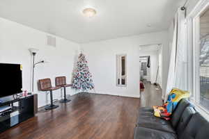 Living room with dark wood-type flooring and baseboards