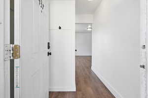 Hall with baseboards and dark wood-style flooring