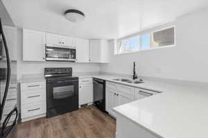 Kitchen with black appliances, white cabinets, dark wood-style flooring, and a textured ceiling