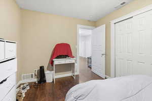 Bedroom with dark wood-type flooring and a closet
