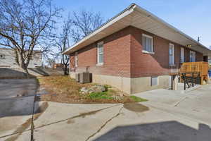 View of side of home with brick siding and a central air condition unit