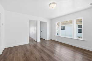 Unfurnished room featuring dark wood-type flooring and a textured ceiling