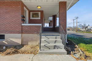 Property entrance with a porch and brick siding