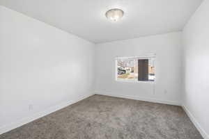 Carpeted spare room featuring baseboards