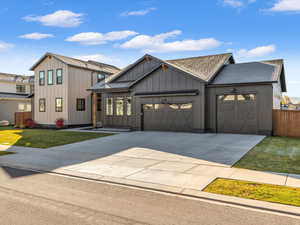 Modern farmhouse style home with board and batten siding, concrete driveway, roof with shingles, and an attached garage