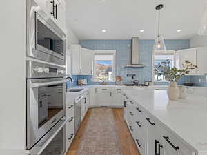 Kitchen featuring light stone countertops, white cabinets, tasteful backsplash, and recessed lighting