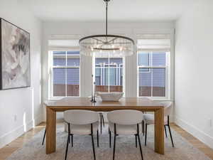 Dining room with light wood-style floors, healthy amount of natural light, and a chandelier