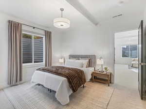Bedroom featuring beam ceiling and light carpet