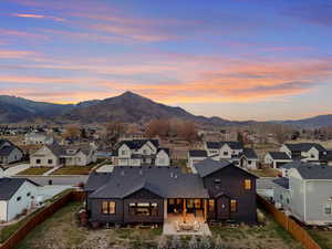 Back of property at dusk with a fenced backyard, a patio, and a mountain view
