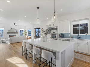 Kitchen with white cabinets, backsplash, a breakfast bar, pendant lighting, and a center island