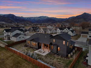 View of front of property featuring a patio area, a mountain view, board and batten siding, and a fenced backyard