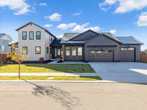 Modern farmhouse style home with board and batten siding, concrete driveway, a garage, and a shingled roof