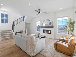 Living area with stairs, light wood-style floors, a glass covered fireplace, recessed lighting, and a ceiling fan