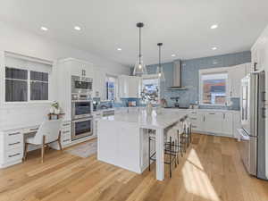 Kitchen with a breakfast bar, white cabinetry, pendant lighting, and recessed lighting