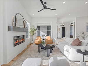 Living area featuring a glass covered fireplace, wood finished floors, recessed lighting, a ceiling fan, and a chandelier