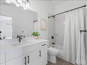 Bathroom with shower / bath combo with shower curtain, dark tile patterned flooring, and vanity