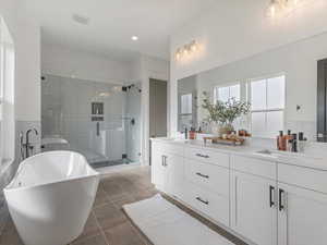 Full bathroom with a freestanding tub, double vanity, a shower stall, and light tile patterned floors