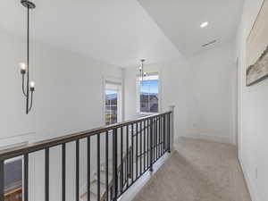 Hallway featuring recessed lighting, light colored carpet, an upstairs landing, and a chandelier