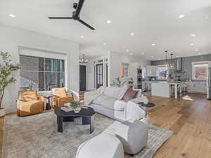 Living room featuring light wood-style flooring, a chandelier, ceiling fan, and recessed lighting