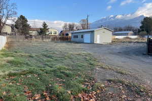 Fenced backyard featuring an outbuilding, a mountain view, a residential view, and driveway