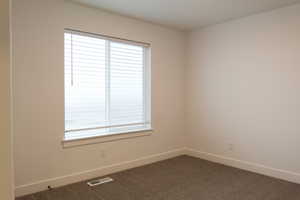 Carpeted spare room featuring baseboards