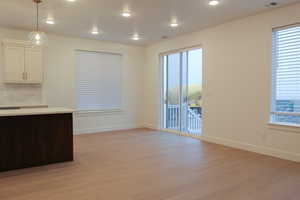 Unfurnished dining area featuring light wood finished floors, healthy amount of natural light, and recessed lighting
