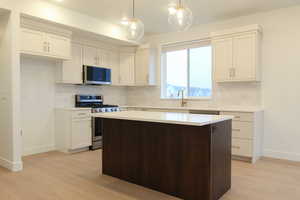 Kitchen with appliances with stainless steel finishes, white cabinetry, a center island, and decorative backsplash